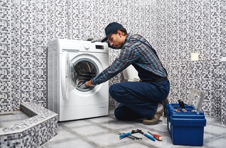 A man is engaged in repairing a washing machine in a bathroom, illustrating laundry appliance repair services in Las Vegas, NV.