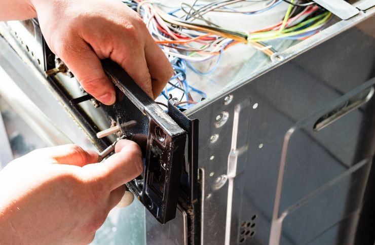 A technician fixes a refrigerator using wires, highlighting small appliance repair services available in Las Vegas, NV.